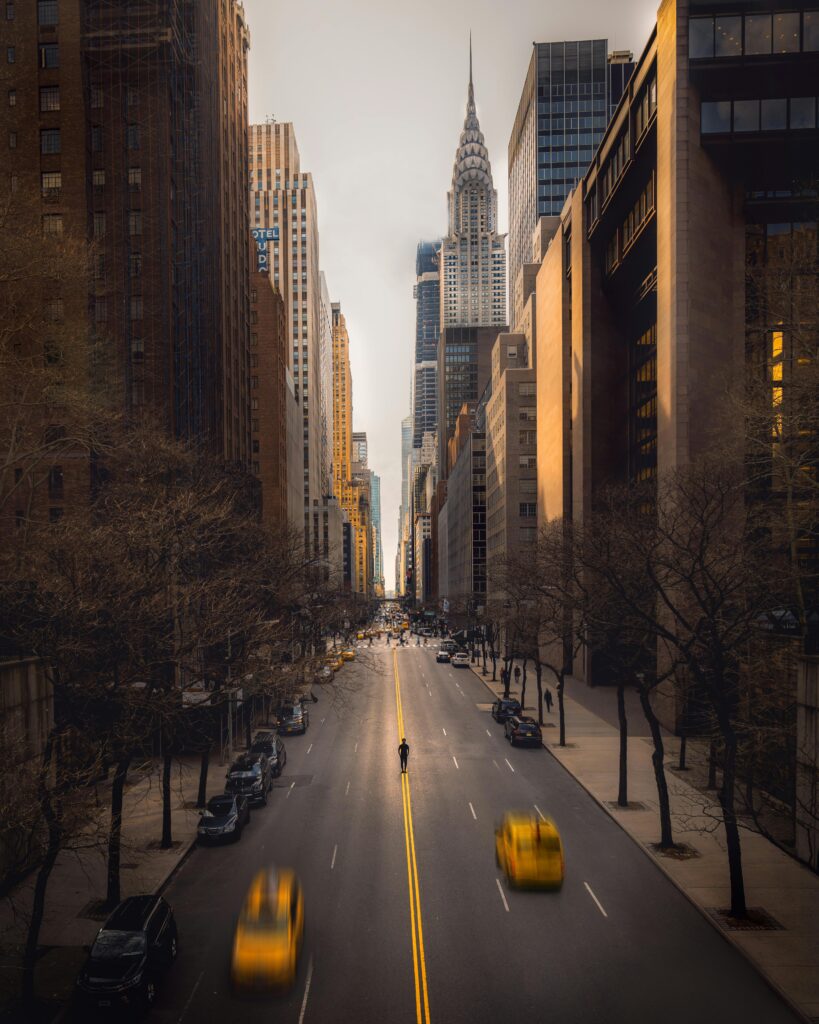A bustling New York City street featuring yellow taxis, modern skyscrapers, and iconic architecture.