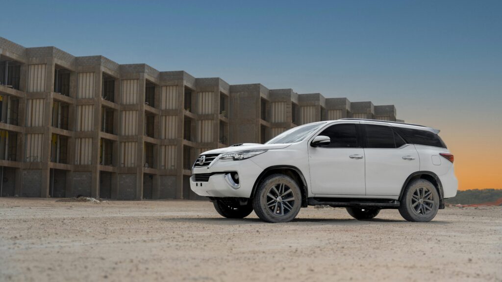 A white Toyota SUV parked in front of a concrete structure during sunset, highlighting its rugged design.